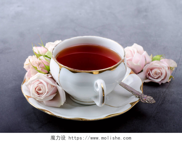 灰色背景上的一杯茶茶时间背景，古色古香的白瓷茶杯，深灰色背景下柔和的粉红玫瑰.
